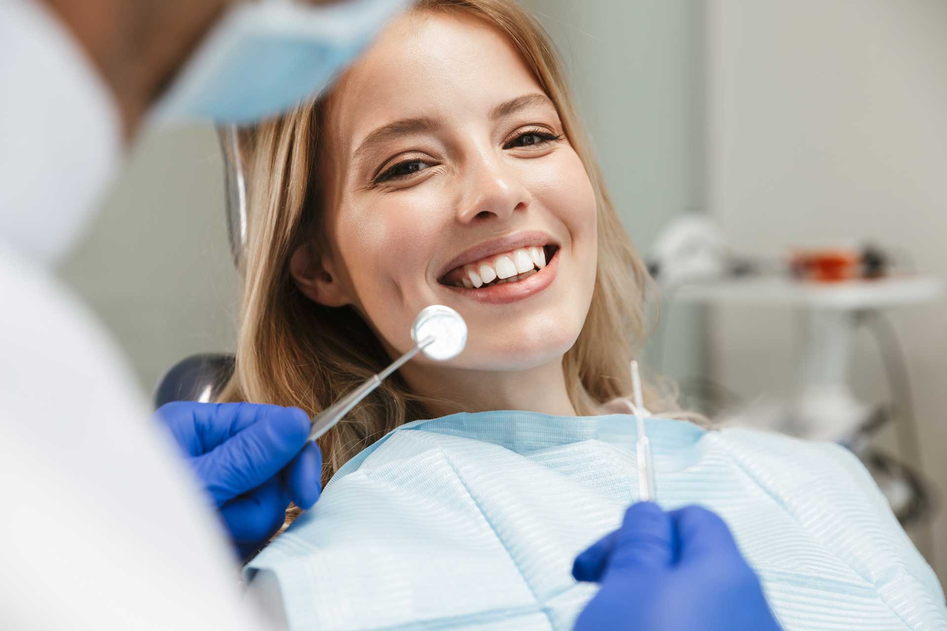 Frau lächelnd in einem Zahnarztstuhl