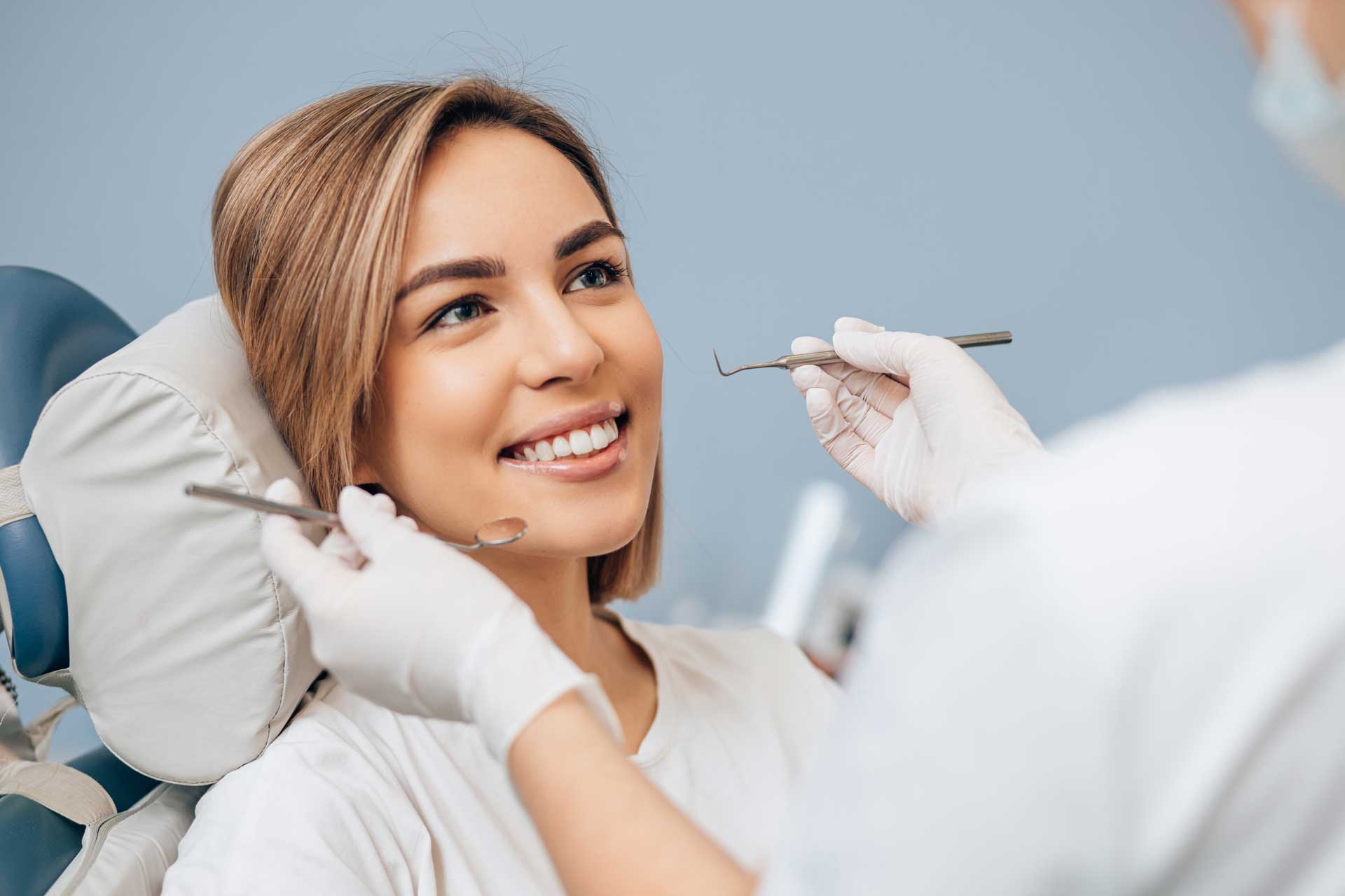 Lächelnde Frau bei einer Behandlung in einer Zahnarztpraxis.